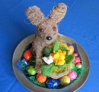 Osterhase auf Teller mit Hühner- und Schokoeiern.